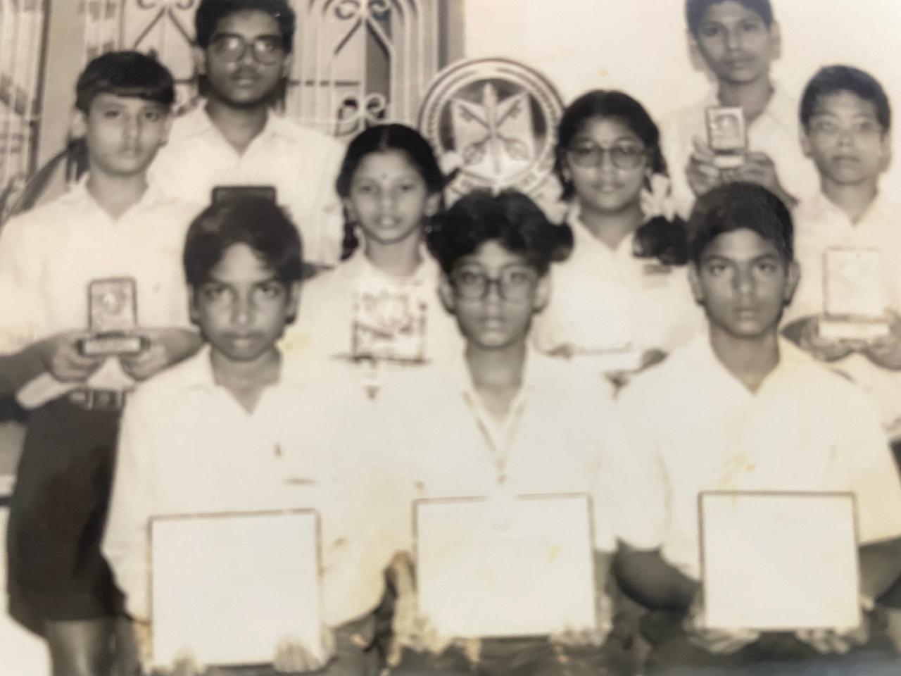 A group photograph from Pushpavalli’s school years, with students holding certificates and awards.